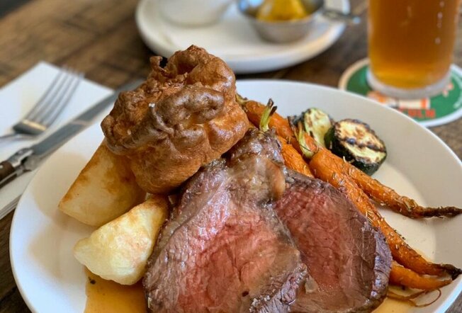 A roast beef pub meal with potatoes, carrots, zucchini and a Yorkshire pudding.