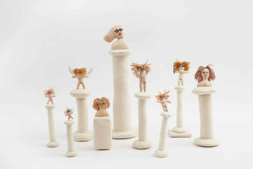 Little white plinths with small comical figures and heads on top. 