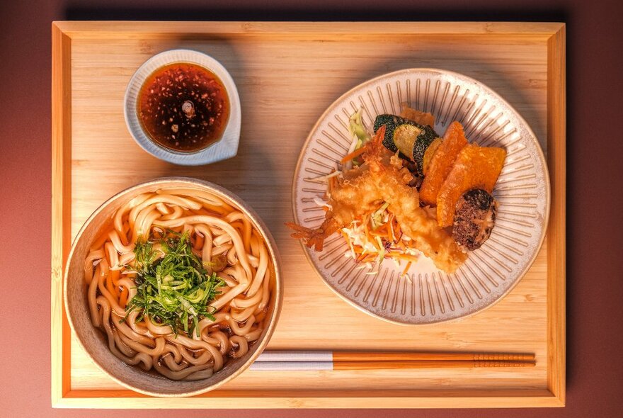A wooden tray with tempura and a bowl of udon noodles on it