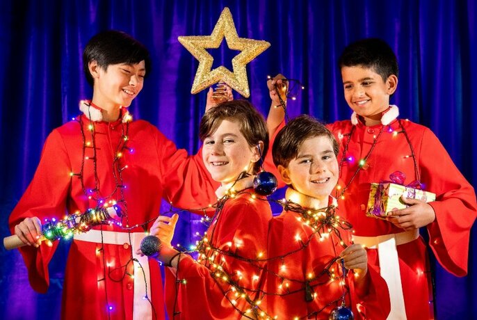 Choirboys dressed in red robes with Christmas lights and stars.
