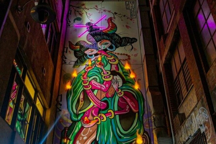 A mural of a strange glowing creature in a laneway.