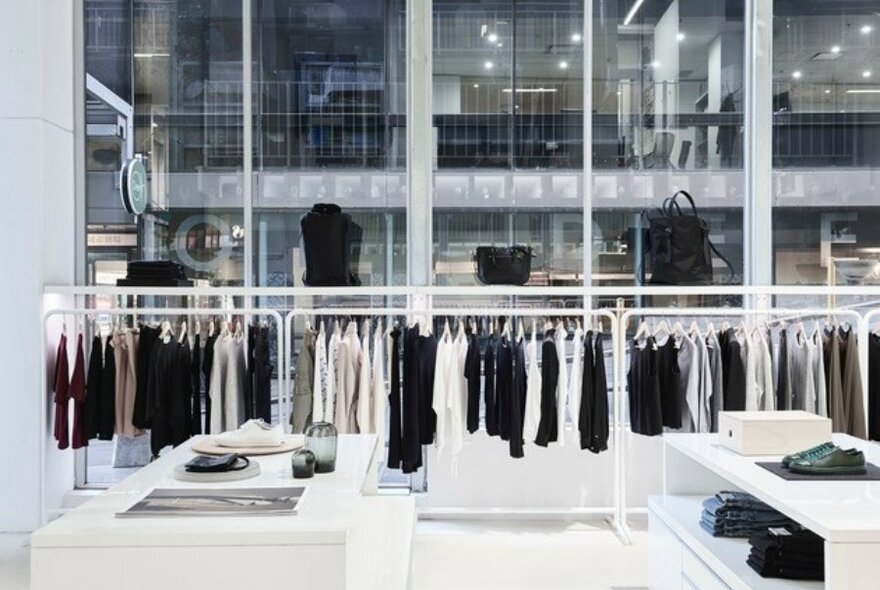 A retail boutique with black white and grey clothing on minimalist displays.