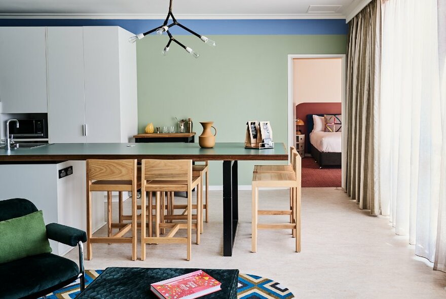 A hotel room with quirky decor, green walls and a light fixture modelled on a tree branch.