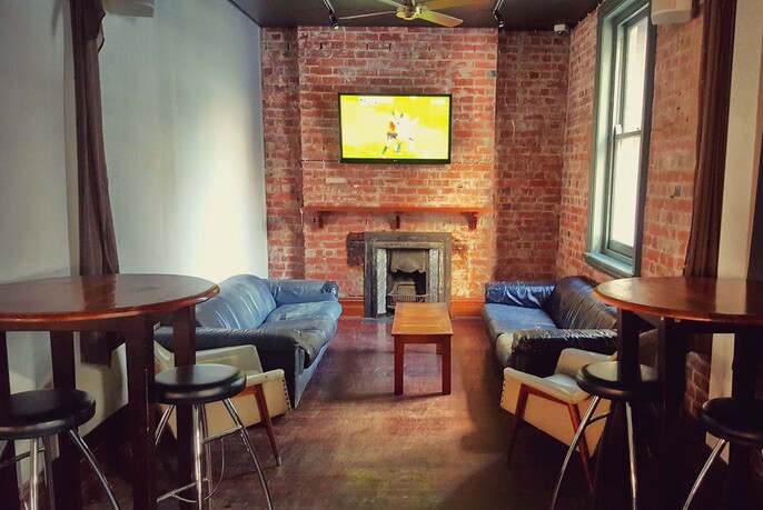 Pub venue with brick walls, large-screen TV, couches, tables and chairs.