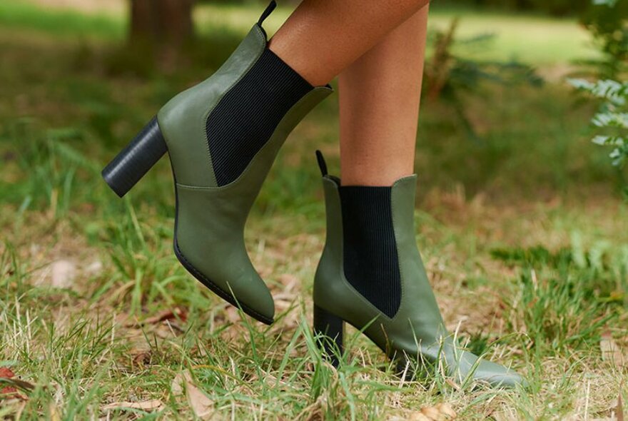 A close up of green and black heeled boots. 