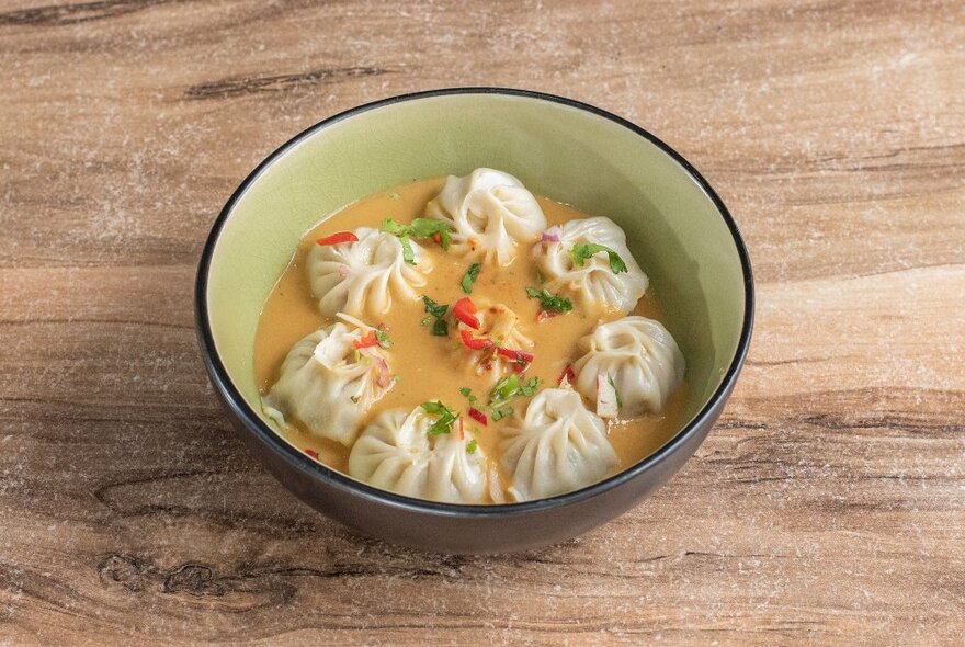 A bowl of dumplings in a soup broth.