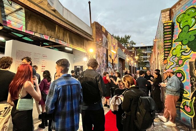 People gathered in a graffitied laneway.