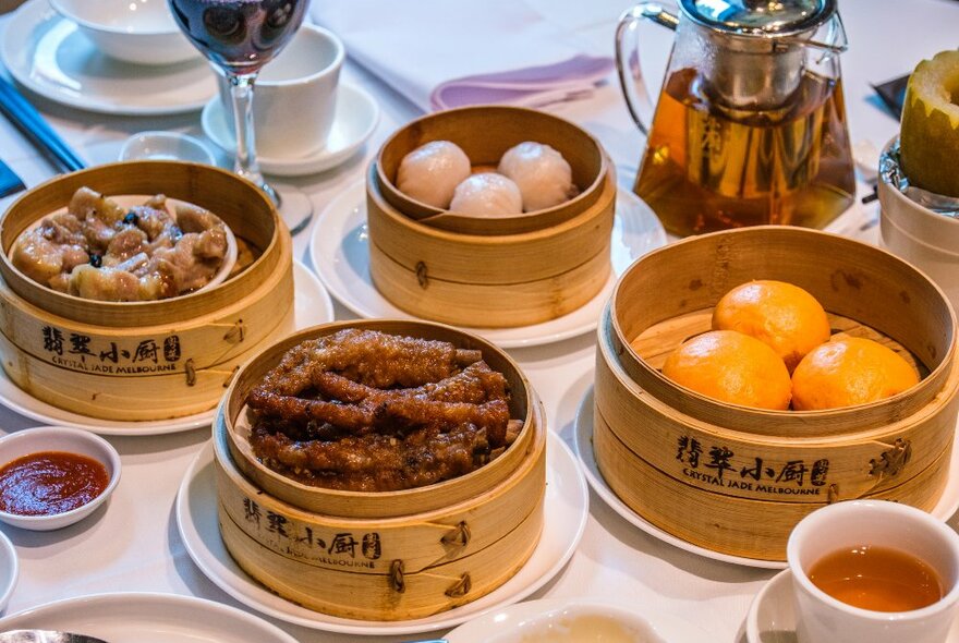four steam baskets in a yum cha restaurant with dumplings, chicken feet and teamed buns in them