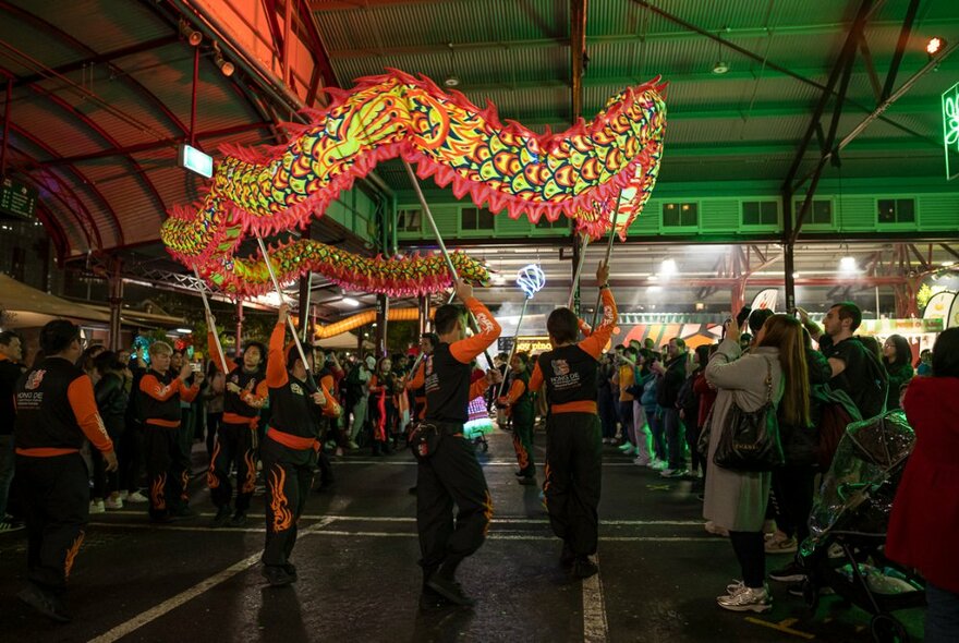 A Chinese dragon dance making its way through the darkened market at night.