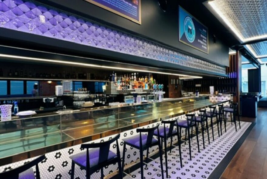 A long tiled bar with seating.