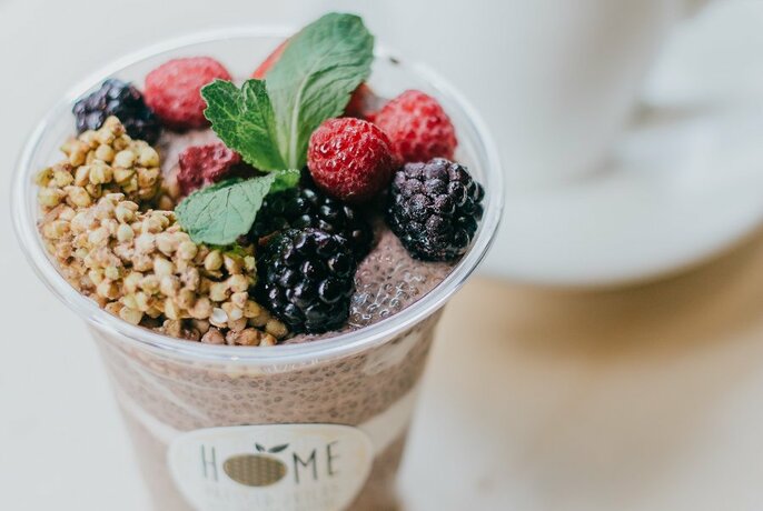 A chia pudding in a takeaway cup with fresh berries.