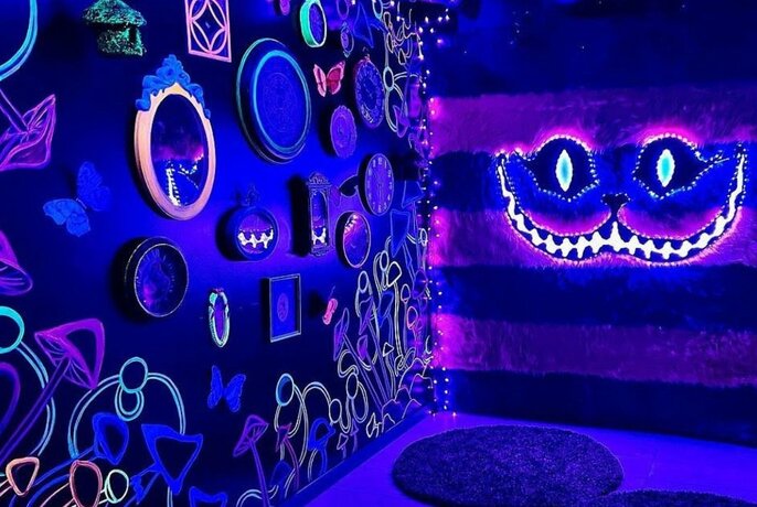A blue lit room decorated with mirrors, neon lights and other wall decorations.