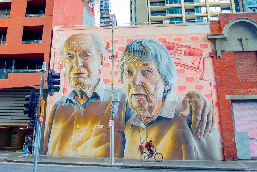 A large mural of an elderly couple, the man has his arm over her shoulder.