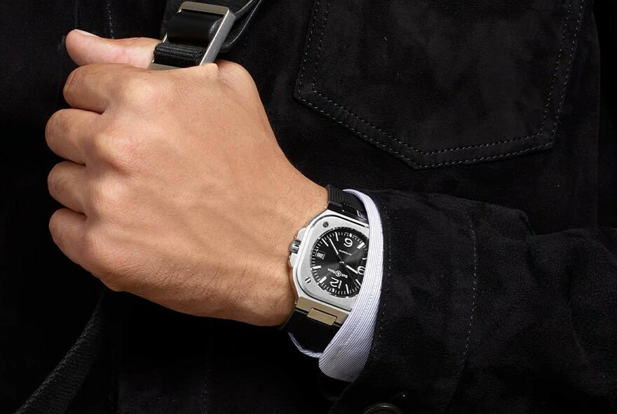 Male model's hand with black-faced wristwatch and cuff.