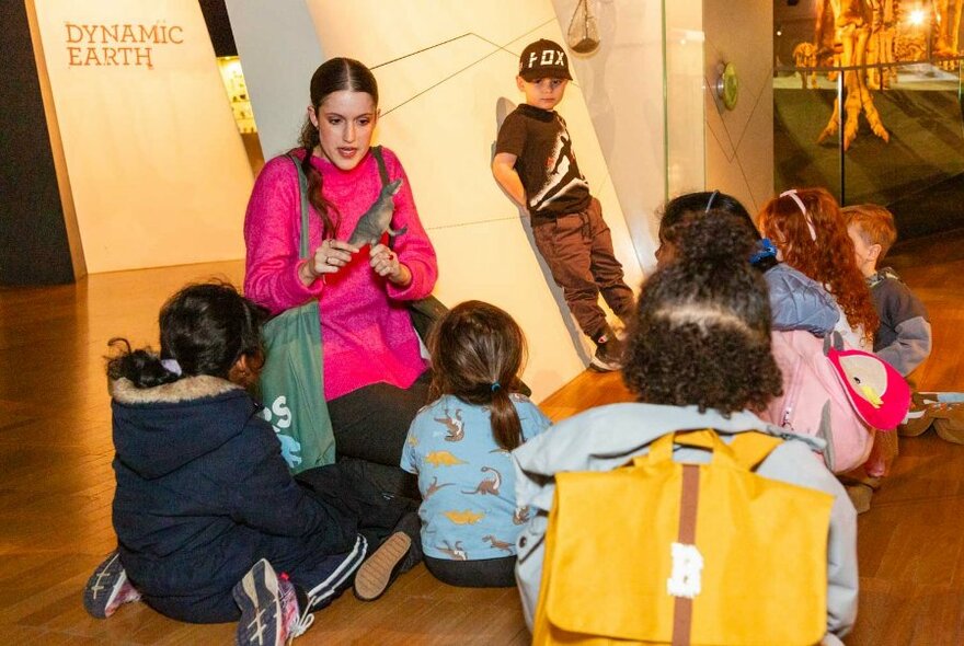 Children seated around a presenter holding a dinosaur.
