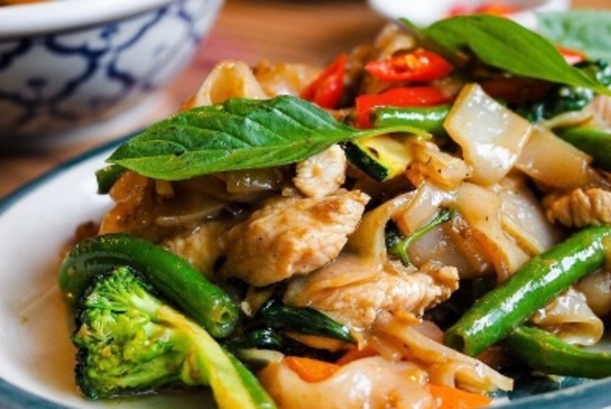 A close up of a Thai chicken dish with chillies, broccoli and Thai basil.