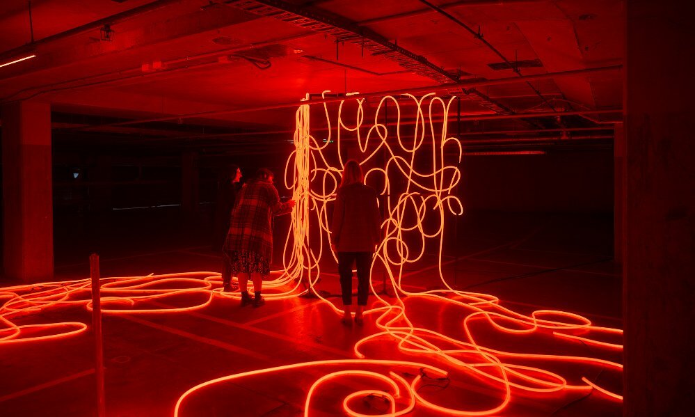 a group of friends are looking at a glowing red sculpture