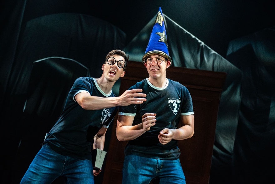 Two actors onstage as characters from Harry Potter, one wearing a blue wizard's hat with gold stars.