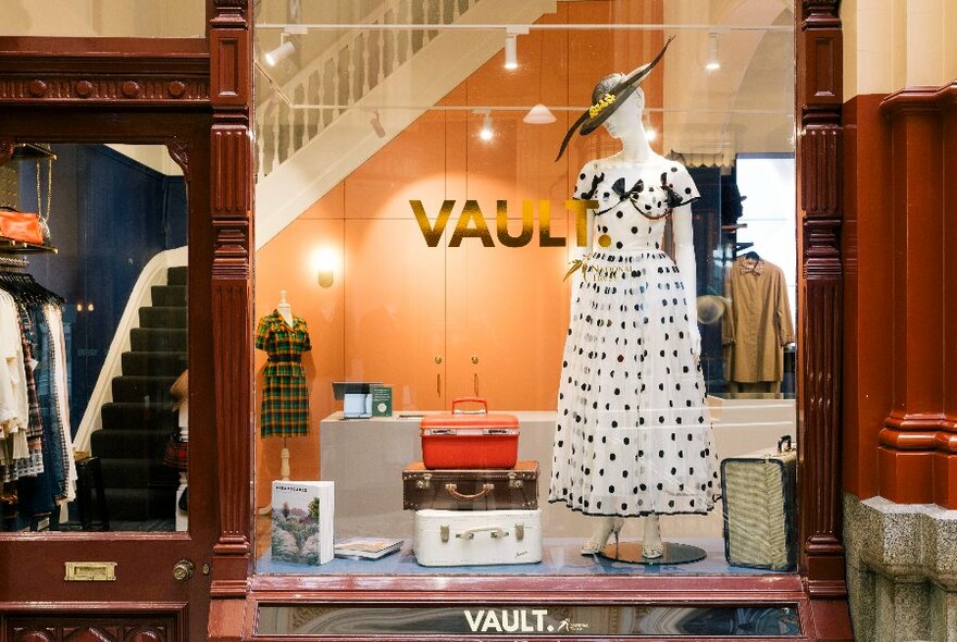 Window exterior of the shop Vault showing a display of a vintage polka dot frock and hat on a mannequin.