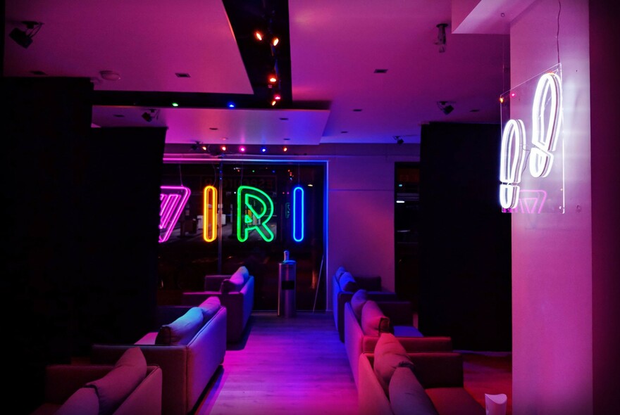 Dimly-lit interior of Viri VR showing couches and a neon sign on a wall.