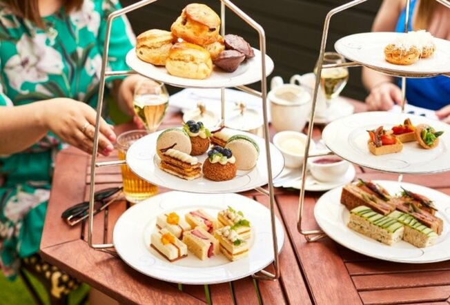 People dining with tired high tea trays of sweet and savoury bites.