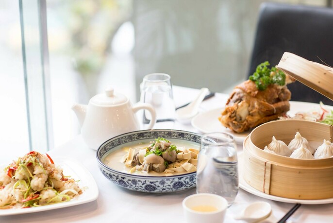 Table at window, filled with Asian dishes and teapot.