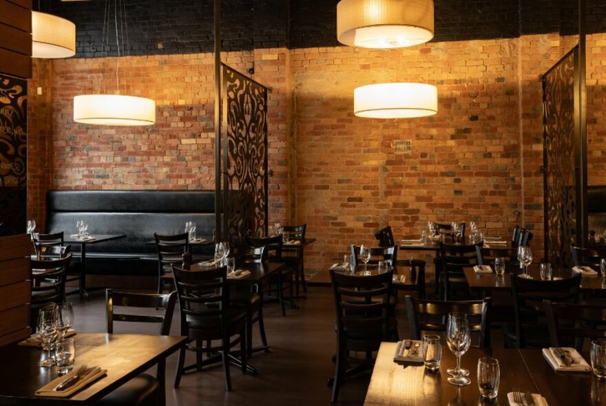 An empty brick restaurant with large lights overhead and warm tones