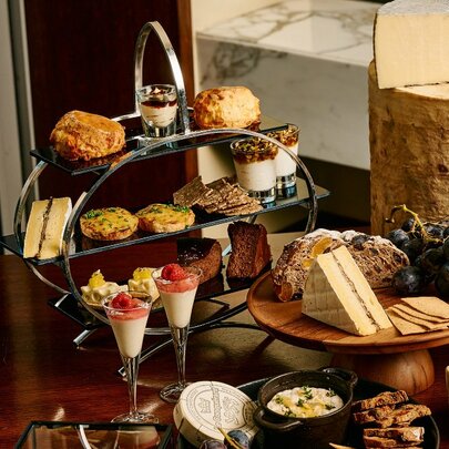 A silver tray with high tea treats and cheeses.