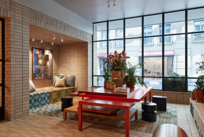 Interior of hotel foyer with red coffee table and bench in centre and inset banquette to the left.