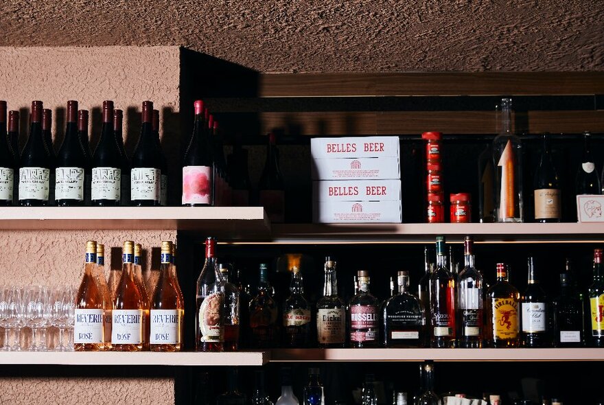 Close up of two shelves of wine and liquor bottles.