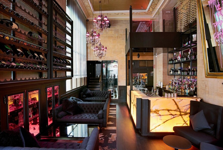 The Whiskey Boutique lounge at Ms Collins with leather couches, occasional tables and an illuminated bar.