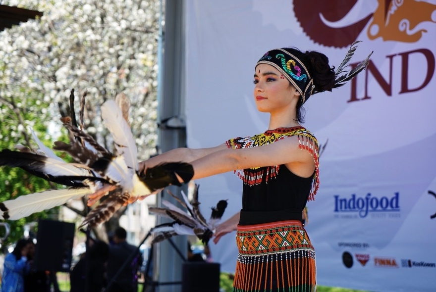 A person in Indonesian national dress performing on an outdoor stage. 