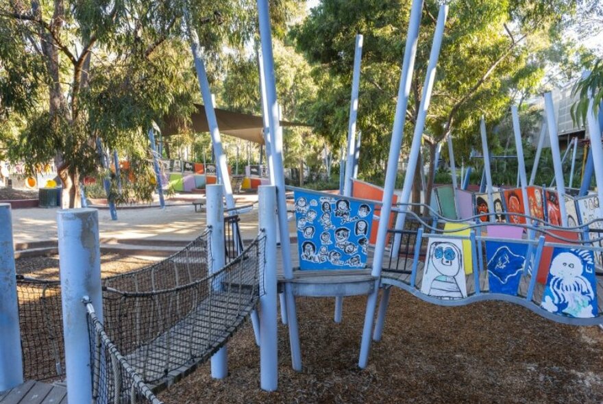 A colourful playground with a swing bridge and painted murals. 