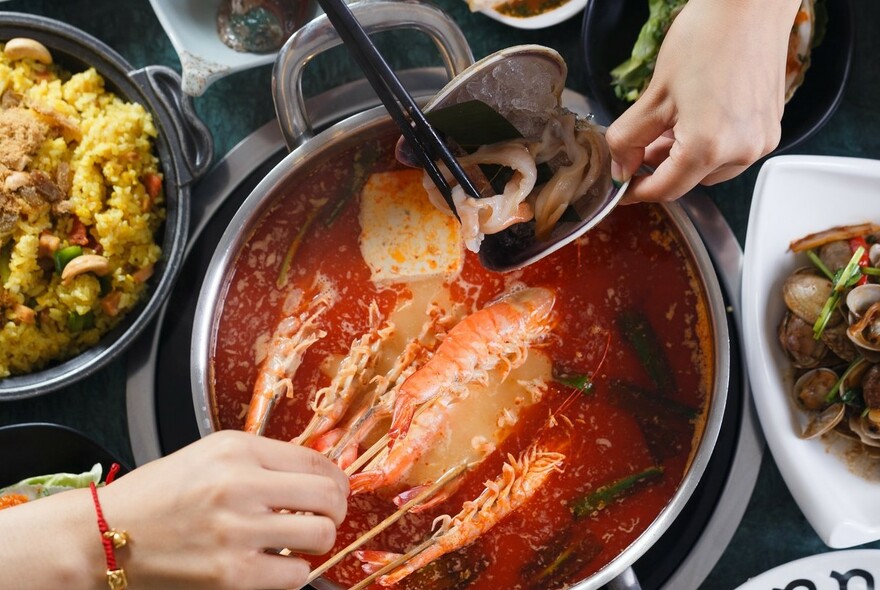 People scooping seafood out of hot pot