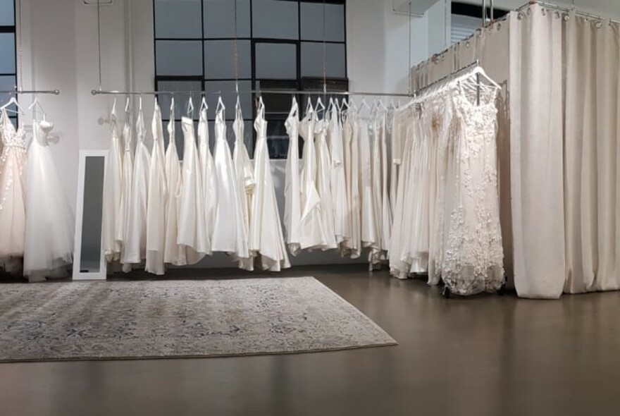 Retail warehouse space with white gowns hanging on rails.