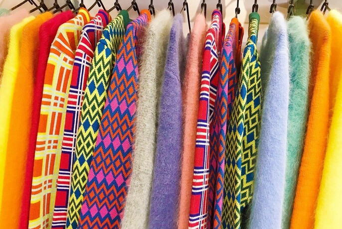 Brightly coloured vintage-style jumpers lined up on hangers.