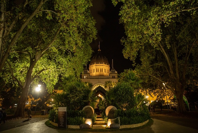 The Royal Exhibition Building heritage fountain and trees spotlit at night.