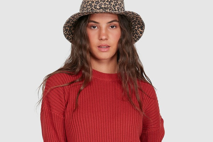 Woman with animal-patterned hat and red top. 