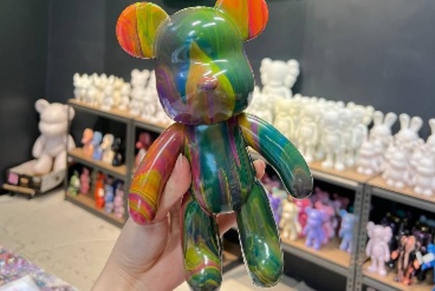 A vinyl bear statue painted with rainbow streaks.