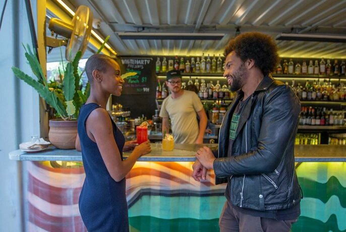 Two people enjoying drinks at a container bar in a laneway.