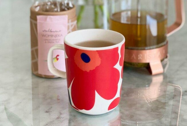 A red floral mug of tea on a marble table.