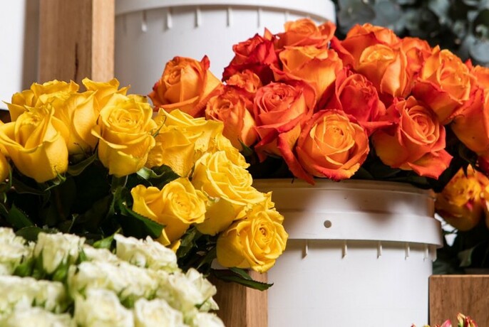 White, yellow and orange roses in white buckets.