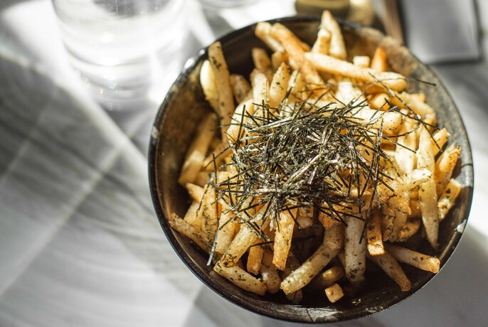 Bowl of fries with shaved seaweed garnish.