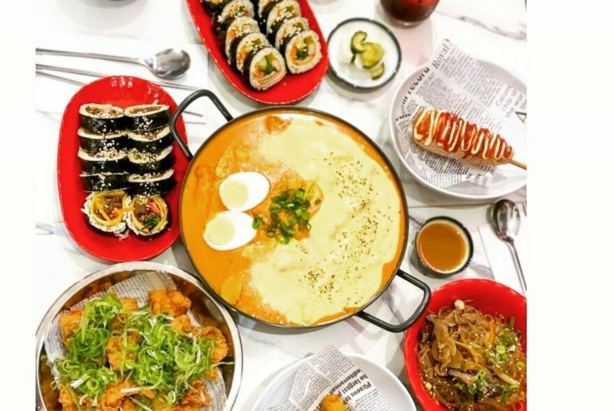 View from above of a dining table that contains several dishes of Korean food.