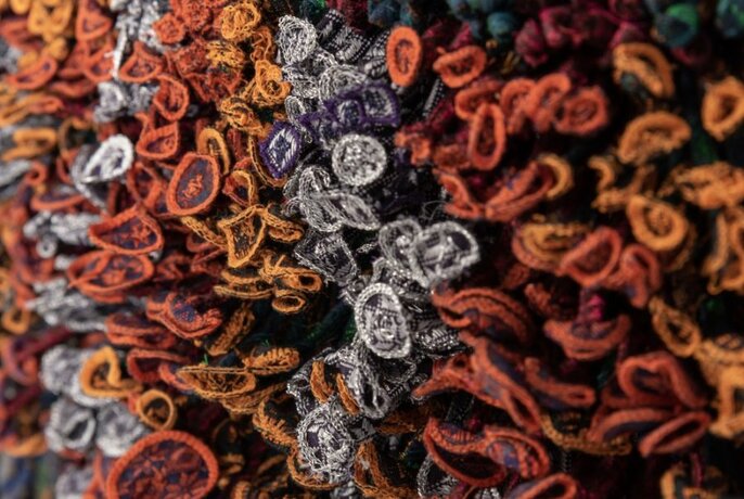 A close-up of a woven rug in shades of orange and grey.