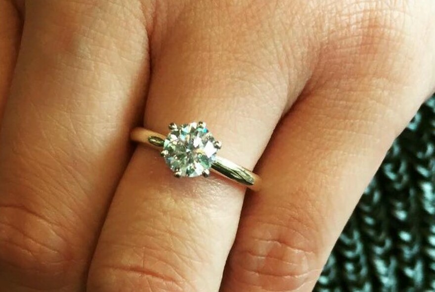 Close up on a gold and diamond ring on a ring finger.