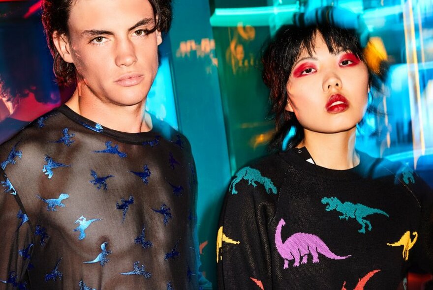 Two models wearing black tops with colourful dinosaurs