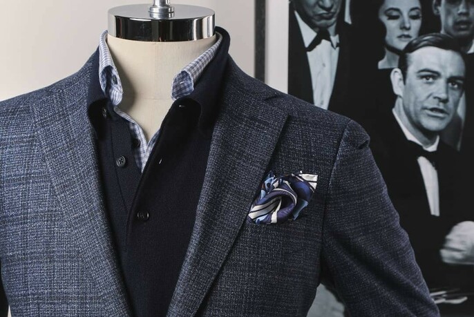 Detail of mannequin wearing blue plaid jacket and accessories, with picture of Sean Connery as James Bond in the background.