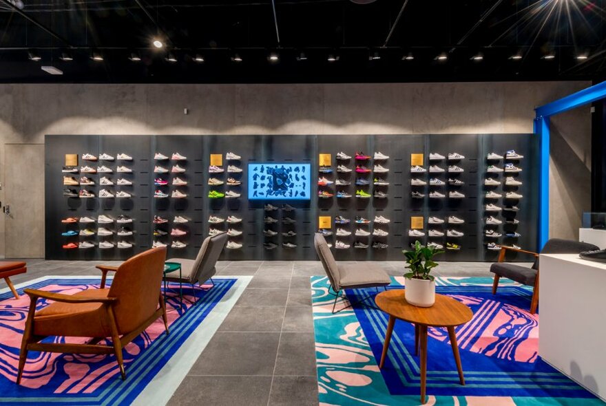 Interior of the Adidas store with a wall of sneakers and colourful rugs 