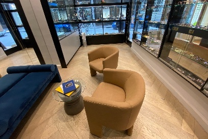 The interior of the Trend Optic shop with two mustard coloured tub chairs and a long deep blue sofa with a small table covered in books between them 